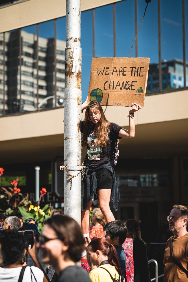 Child protesting climate change with 'we are the change' sign